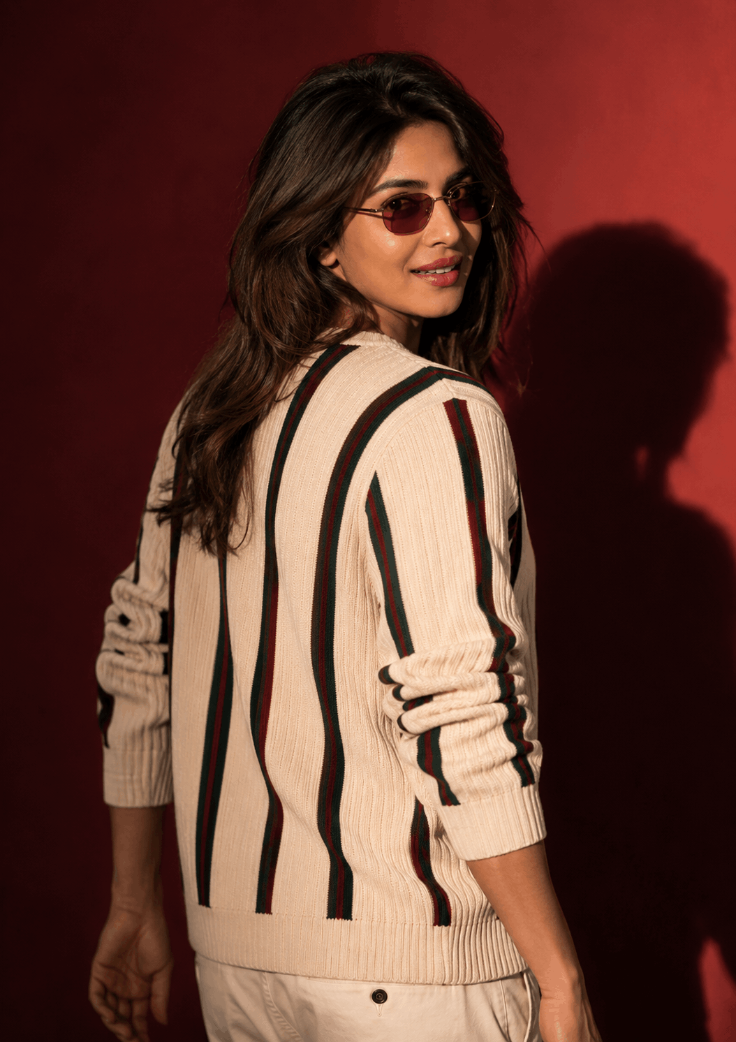 Candid walking pose cream striped sweater example Luxury Editorial Studio Profile Photo of a person in a striped knit sweater glancing back over the shoulder